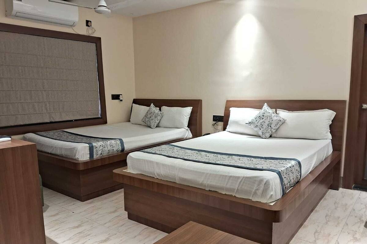 A hotel room with two beds, a desk, and a chair.