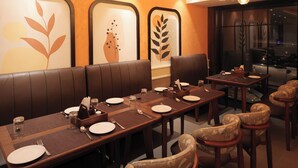 A restaurant with a long table, multiple chairs, and a high ceiling with hanging lights. - la mishika (Tarapith)