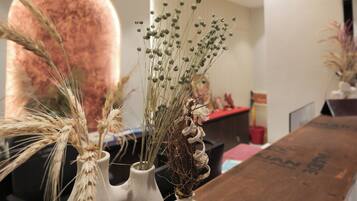 A reception area with a wooden reception desk, a white vase with dried plants, and a modern chandelier.
