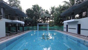 A swimming pool with a covered area, surrounded by trees and a building with a balcony. - la mishika (Tarapith)