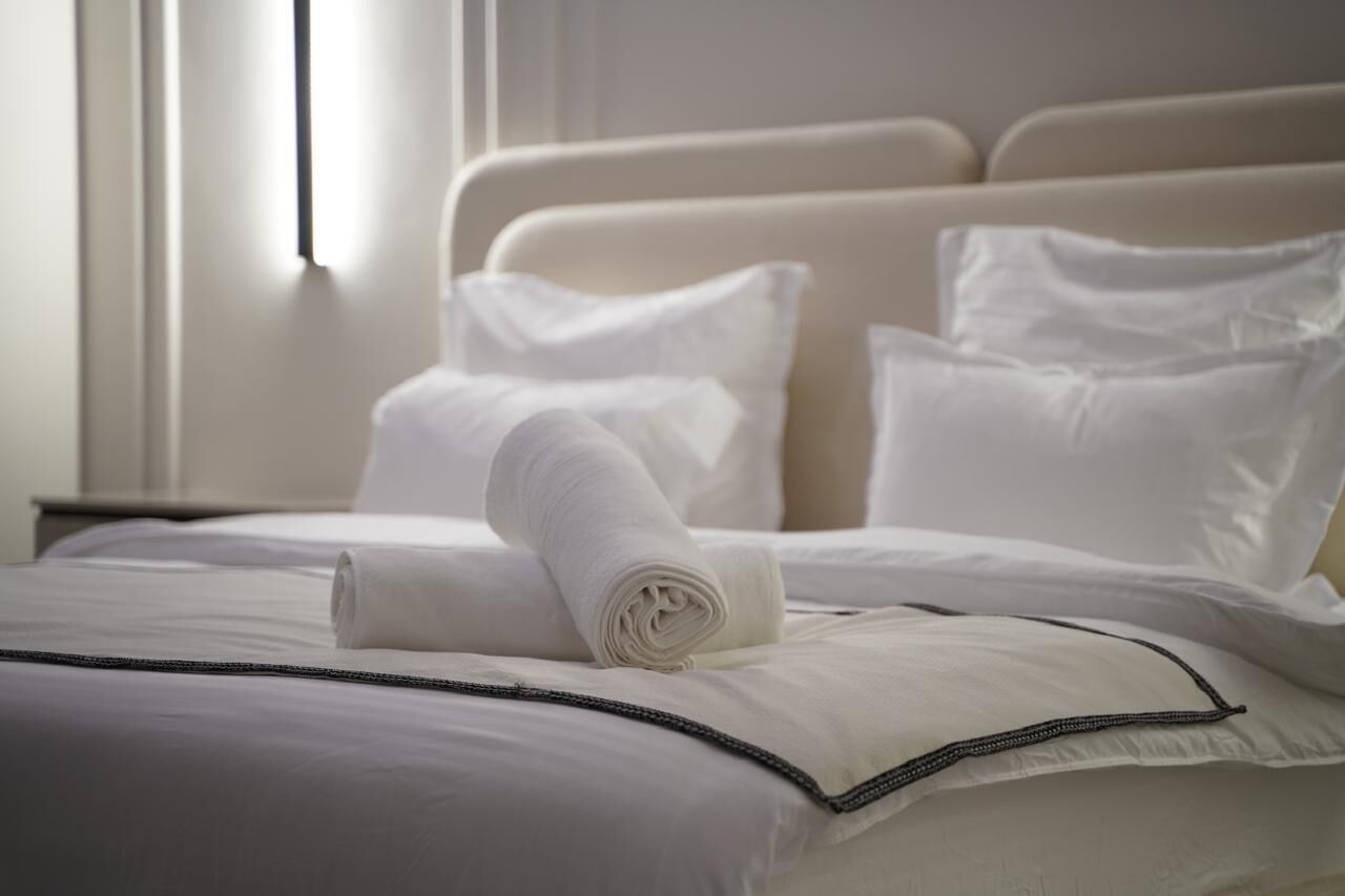 Un lit bien fait, avec des draps blancs et une serviette enroulée posée sur le dessus.