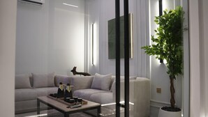 Una sala de estar moderna con un sofá gris, una mesa de centro con botellas y una planta en maceta.