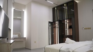 Una habitación de hotel moderna con una cama grande, un tocador con espejo y un armario con espejo.
