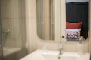 A bathroom with a mirror, a sink, and a shower. - Guestready - Casa das Arcadas (Ponta Delgada)
