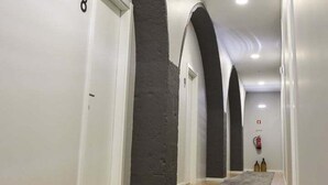A hallway with white walls, dark arches, and a grey carpet. - Guestready - Casa das Arcadas (Ponta Delgada)