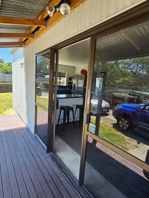 Una terrazza esterna moderna con una porta scorrevole in vetro che dà su una zona cucina.