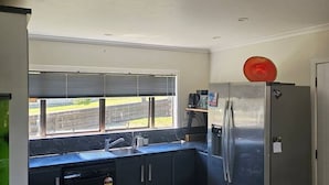 Eine kleine Küche mit Spüle, Kühlschrank und einem Fenster mit Jalousien.