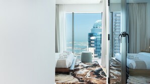 Una habitación de hotel moderna con un amplio ventanal corredero que da a un balcón y vistas a la ciudad.