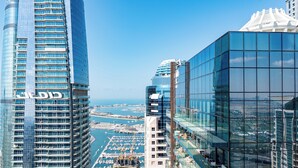 Un edificio alto con fachada de vidrio, una marina con barcos y un cielo azul despejado.