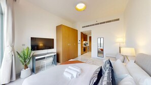 A modern hotel room with a large bed, a desk, a TV, a sofa, and a mirror. - Modern Studio l Community Views l Free Gym, Pool (Studio City)