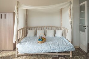 Un lit à baldaquin, avec des oreillers et un panier contenant divers objets.