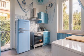 Une cuisine de taille réduite avec un réfrigérateur bleu, une cuisinière et une machine à café.