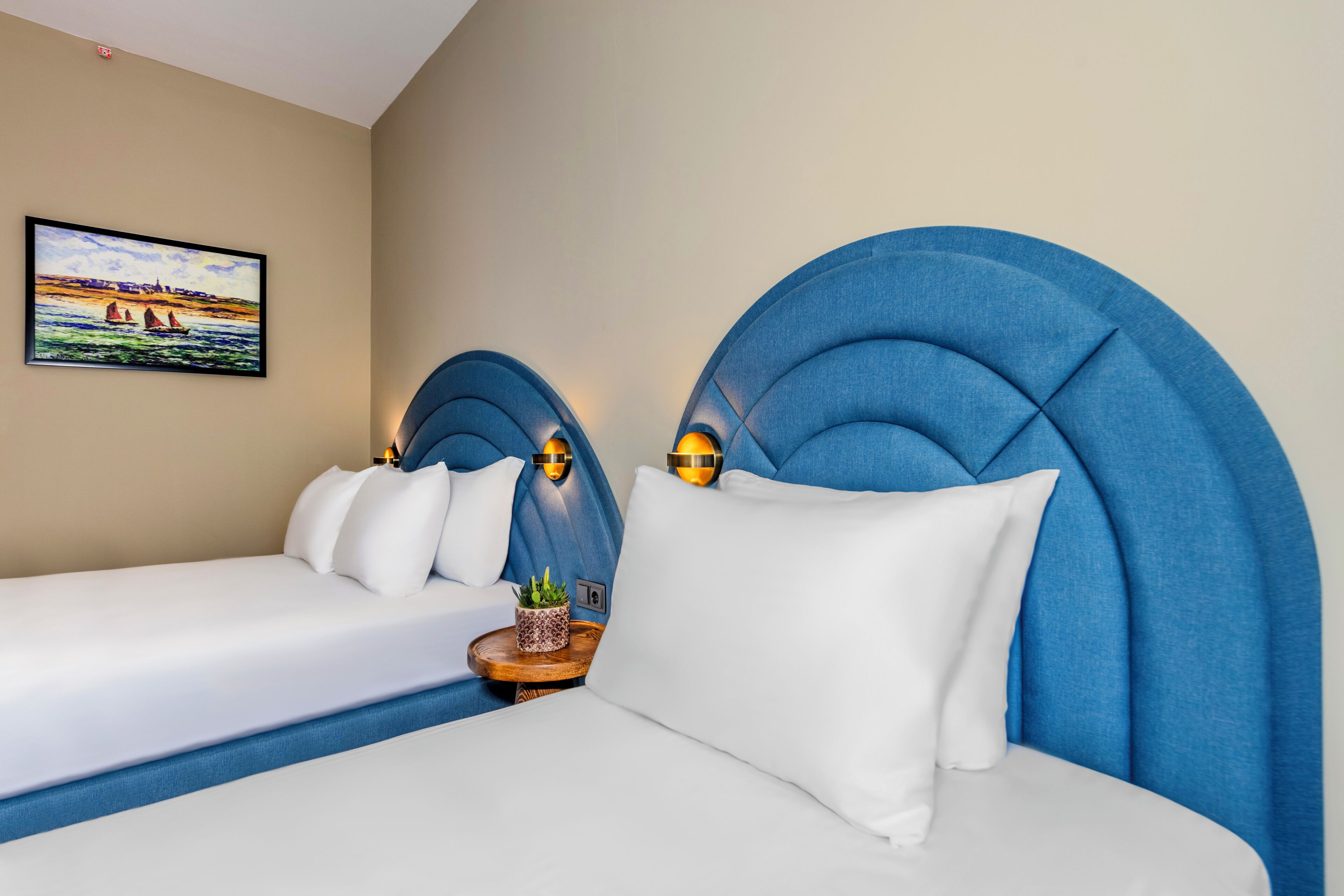 A hotel room with a large bed, a smaller bed, and a headboard with built-in lighting.