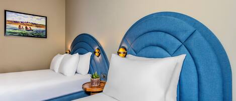 A hotel room with a large bed, a smaller bed, and a headboard with built-in lighting.