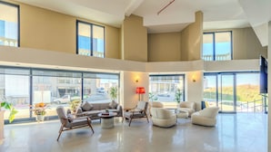 A spacious, modern living area with large windows, comfortable seating, and a view of the outside. - Nenesa Hotel İstanbul Airport  (Arnavutkoy)