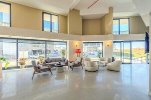 Un salón amplio y moderno con ventanas grandes, asientos cómodos y vistas al exterior.