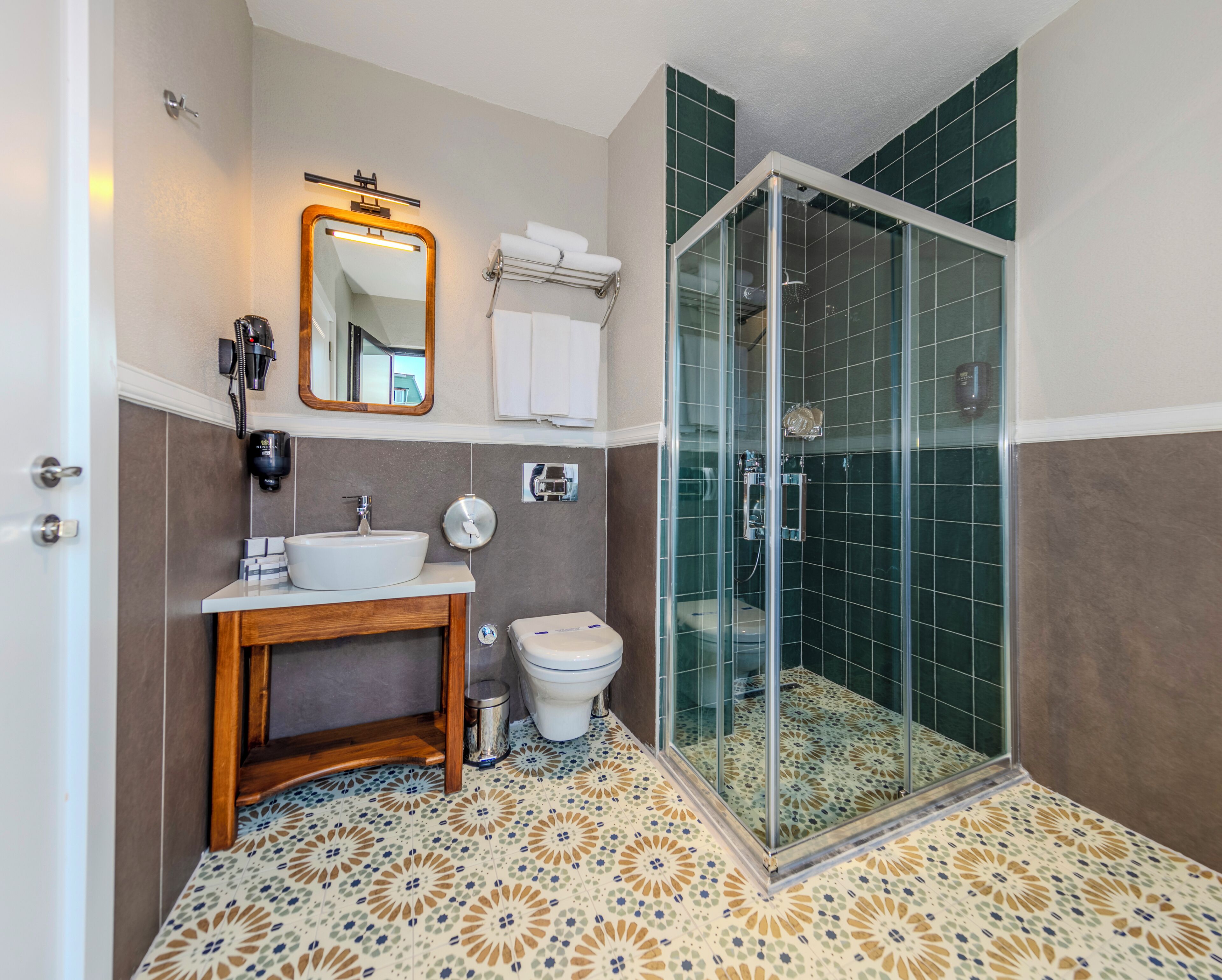 A bathroom with a sink, mirror, toilet, and a glass-enclosed shower area.