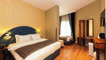A hotel room with a large bed, a desk, a chair, a mirror, and a small refrigerator.