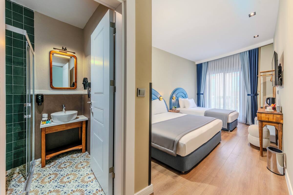 A hotel room with a bathroom, a bed, a bedside table, a chair, and a desk.