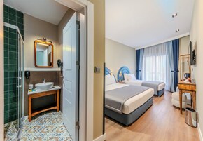 Una habitación de hotel con baño, una cama, una mesita de noche, una silla y un escritorio.