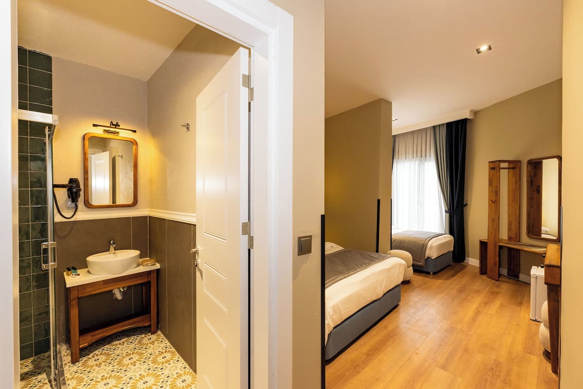 A hotel room with a bathroom, a bed, and a mirror.
