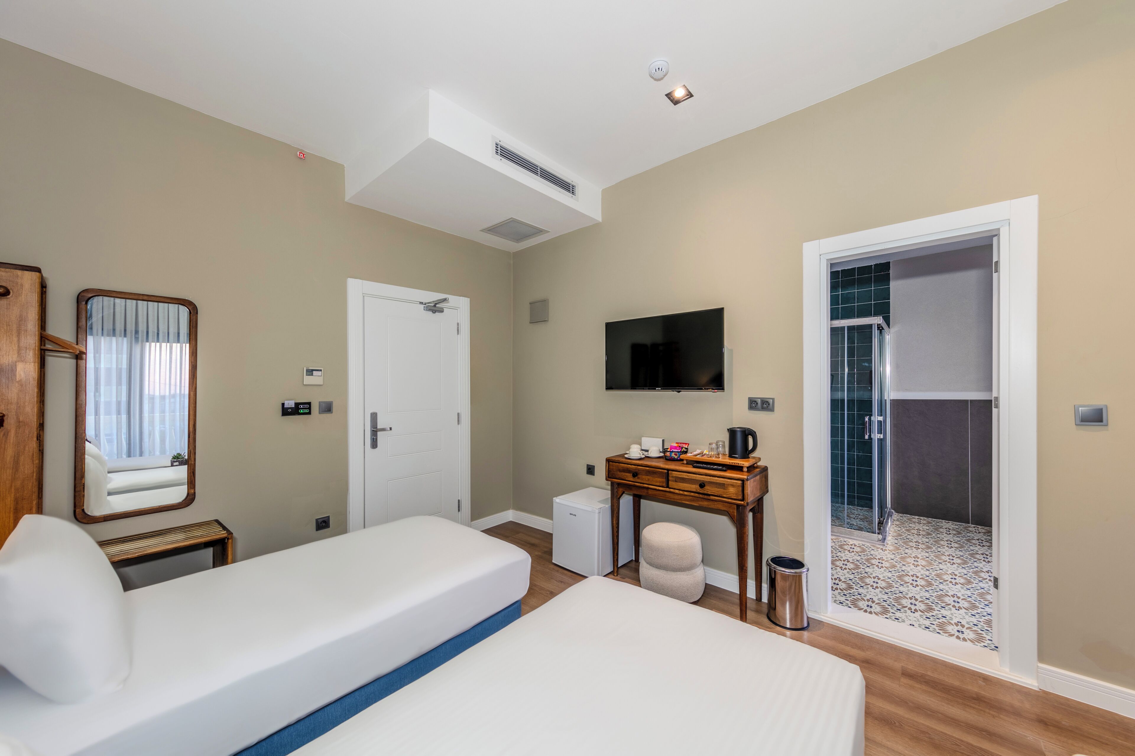 Camera d'albergo con due letti, una scrivania, un televisore, zona doccia e condizionatore.