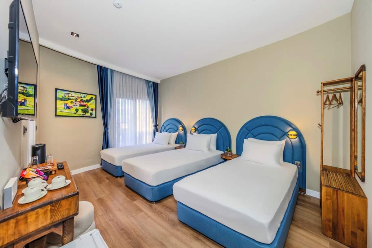 A hotel room with two beds, a wooden desk, a television, and a painting on the wall.