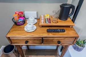 Un escritorio de madera con una cafetera, un teclado y diferentes alimentos.