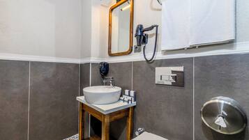 A bathroom with a white sink, wooden vanity, a toilet, a mirror, and a towel rack.