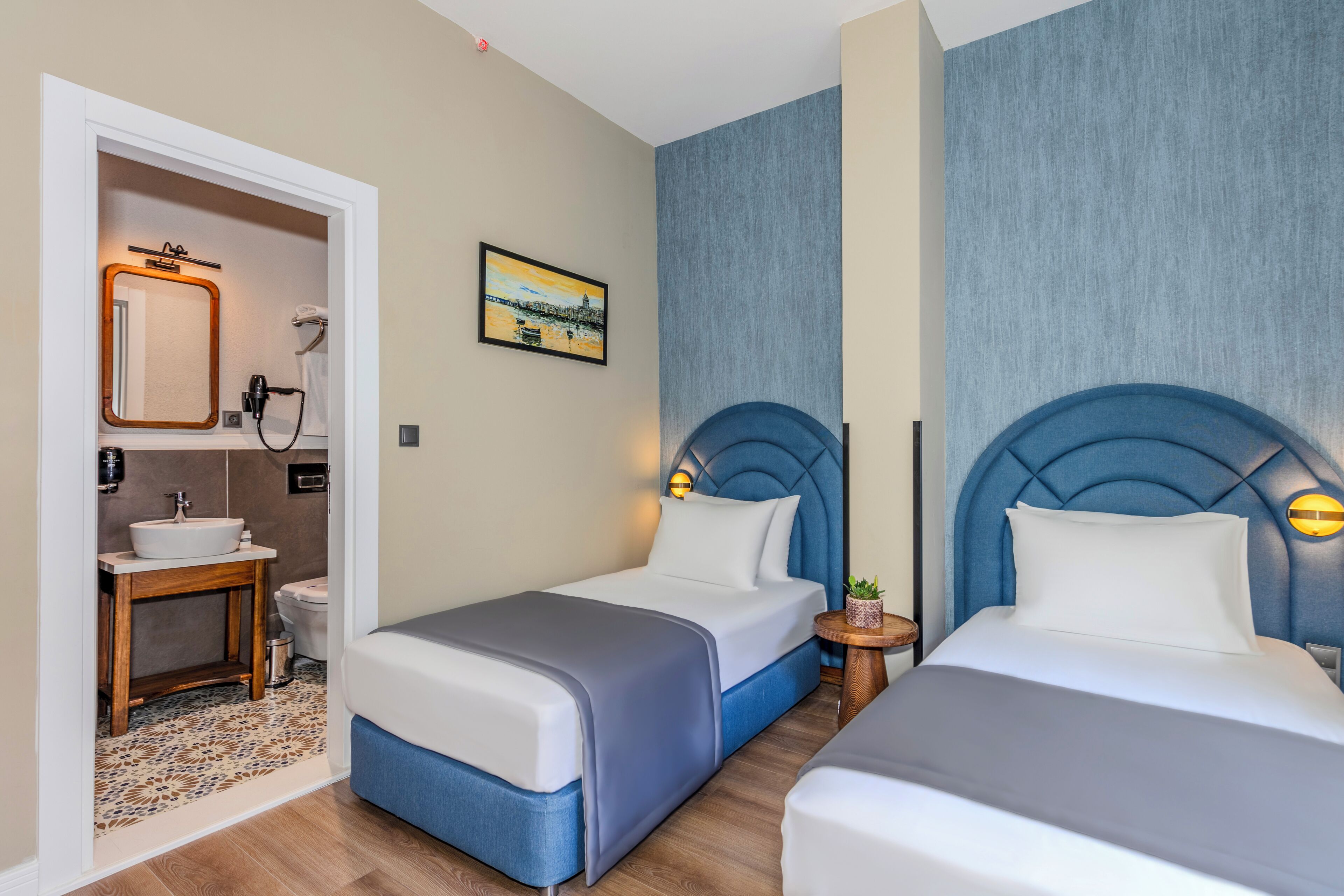 Een hotelkamer met twee bedden, een badkamer en een kleine tafel met een plant.