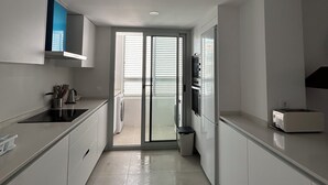 Et moderne køkken med hvide skabe, en sort bordplade og en indbygget ovn.
