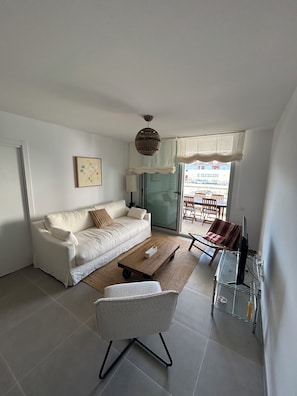 A living room with a white sofa, a coffee table, a TV, and a chair. - 🏖️ New Modern House with Pool near Arenal Beach – Long Stays (11+ nights). (Badia de Xàbia)