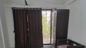 A room with a large sliding door, a wooden bench with a cushion, and a tiled floor. - Wellnessghar (Panvel)