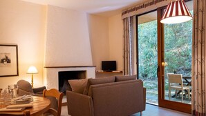 Ein Wohnzimmer mit einer Couch, einem Kamin, einem Fernseher und einem Essbereich mit Tisch und Stühlen.