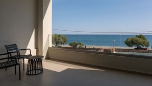 Un balcon avec vue sur la mer, une chaise, une petite table et une plante en pot.