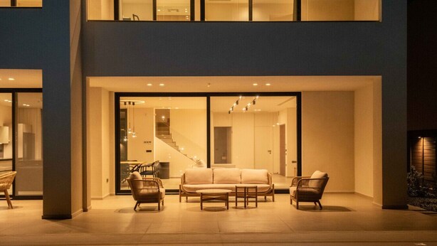 Un espace de vie extérieur moderne comprenant une piscine, un ensemble de canapés et des fauteuils en osier.