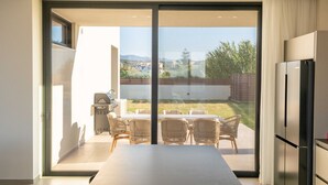 Une cuisine moderne dotée d’une grande porte-fenêtre coulissante qui donne sur un patio extérieur.