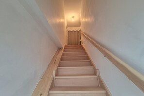 Eine Holztreppe mit Handlauf, die zu einer Tür oben führt.