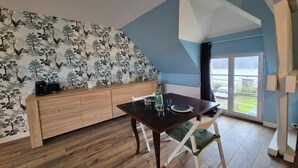 Un comedor con un banco de madera, una mesa con sillas y vistas al exterior por un ventanal.