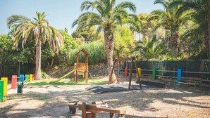 Un parque infantil con columpios, un tobogán y un sube y baja.