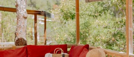 A wooden deck with a red sofa, a wicker basket, and a straw hat.