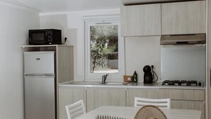 Eine kleine Küche mit Kühlschrank, Mikrowelle, Spüle und Herd.