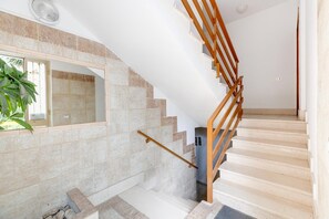 A staircase with a wooden handrail, beige stone steps, and a small alcove with a plant. - Vicino al lungomare, con aria condizionata (Alghero)