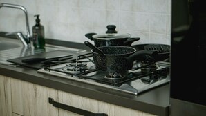 A kitchen with a stove, pots, and a faucet. - The Cat and the Fox: cozy apartment between downtown and station (Vercelli)