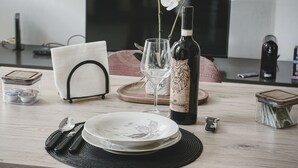 A dining table set with plates, cutlery, a wine bottle, and a vase with flowers. - The Cat and the Fox: cozy apartment between downtown and station (Vercelli)