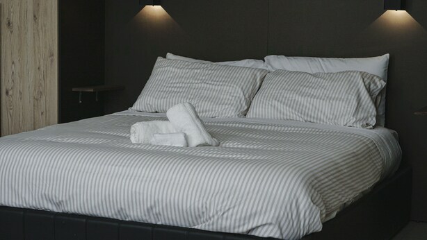 A neatly made bed with striped bedding and two wall-mounted lights. - The Cat and the Fox: cozy apartment between downtown and station (Vercelli)