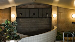 A modern bathroom with a curved sink, tiled walls, and a dark ceiling. - Arima Onsen Maple Arima (Kobe)