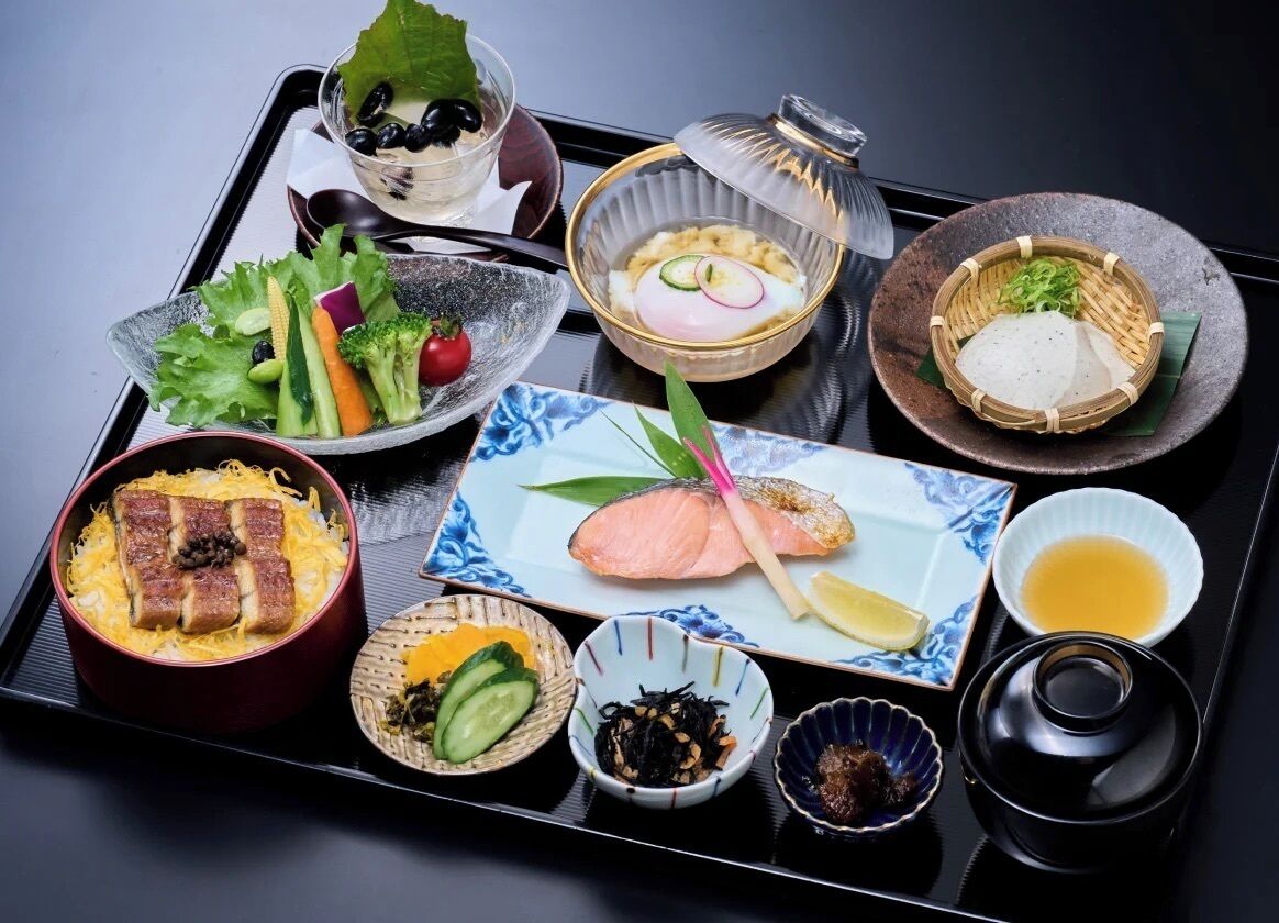 Una bandeja con diversos platos japoneses, incluyendo sashimi, arroz y verduras.