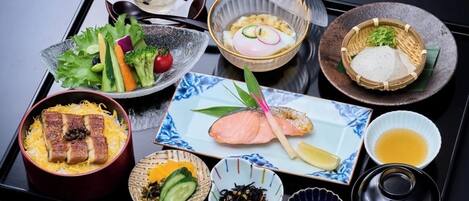 A tray with various Japanese dishes including sashimi, rice, and vegetables.