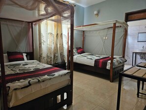 Two four-poster beds with canopy nets, a small bedside table, and a wall-mounted mirror. - EXPRESS VIEW INN (Kampala)
